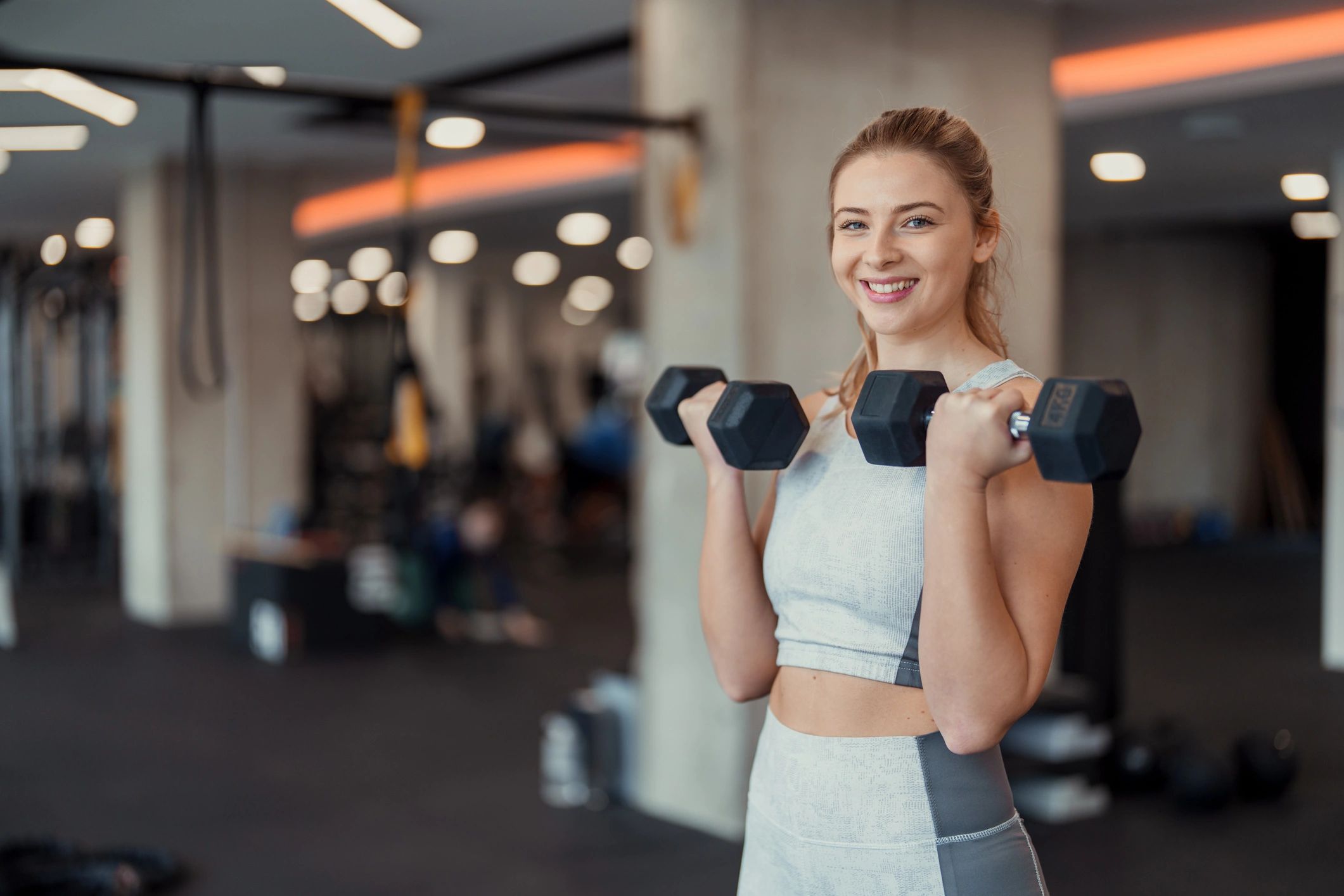 Woman lifting dumbbells in a modern fitness center